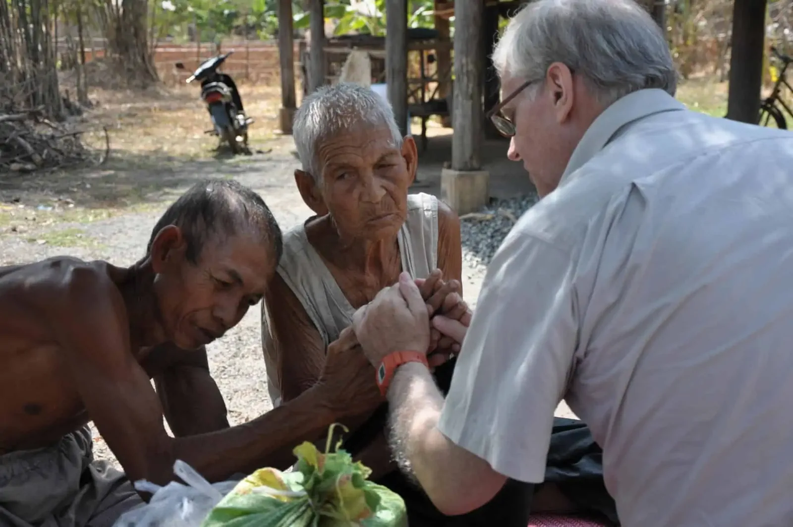 Paul Hughes praying with a mother and his severely disabled son.