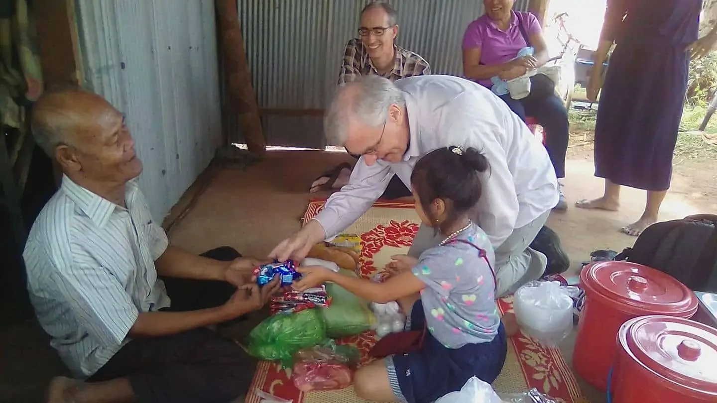 Paul with his foster daughter, meeting one of the elderly, who is disabled, and giving food to him.